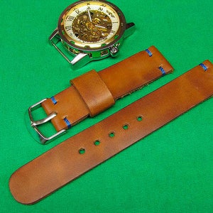 May include: A brown leather watch strap with blue stitching. The strap is designed to fit a watch with a standard 20mm lug width.