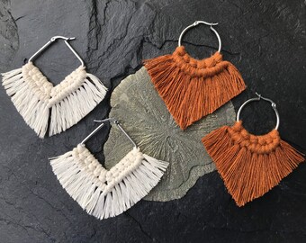 May include: Two pairs of handmade macrame earrings with fringe. One pair is white and the other is brown.