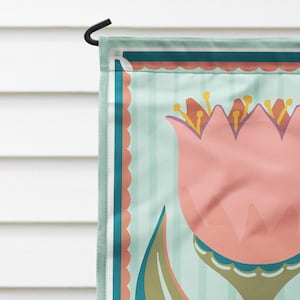 Peut inclure: Un drapeau de jardin d&eacute;coratif avec un motif de tulipe rose. Le drapeau a un fond &agrave; rayures bleu clair avec des accents turquoise et corail. Un crochet en m&eacute;tal noir est attach&eacute; pour l'accrocher.