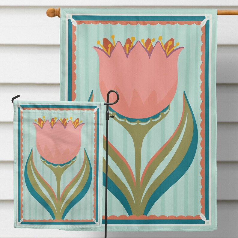 Peut inclure: Deux drapeaux de jardin avec un motif floral. Les drapeaux pr&eacute;sentent une grande tulipe rose avec des feuilles vertes et bleues sur un fond &agrave; rayures bleu clair. Les drapeaux sont encadr&eacute;s d'une bordure festonn&eacute;e.