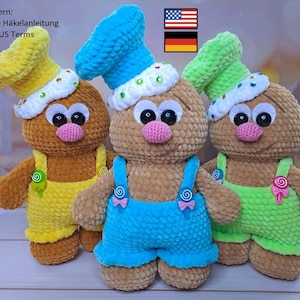 May include: Three crocheted gingerbread man plush toys with different colored hats and overalls. The gingerbread men are brown with pink noses and black eyes. The hats are blue, green, and yellow. The overalls are blue, green, and yellow.
