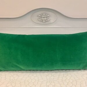 May include: A bright green velvet lumbar pillow on a white bed with a white headboard.