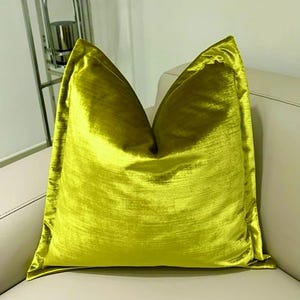 May include: A bright yellow velvet pillow with a square shape and a smooth, silky texture.