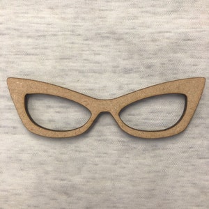 May include: A pair of wooden cat's eye glasses, with a light brown colour, on a white textured background.