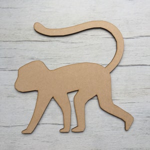 May include: A brown wooden cutout of a monkey in a walking pose. The monkey has a long tail and is facing to the right.