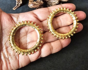 Puede incluir: Dos brazaletes de metal dorado con una superficie texturizada y una fila de pequeñas cuentas redondas alrededor del borde.