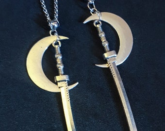 May include: A pair of silver earrings with crescent moon and sword charms hanging from silver chains.