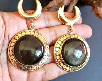 May include: A pair of gold earrings with a crescent moon design and a round black stone set in a gold frame.