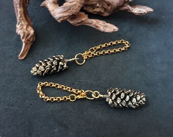 May include: Two gold chains with a pine cone charm on each end. The pine cones are silver and have a detailed design.