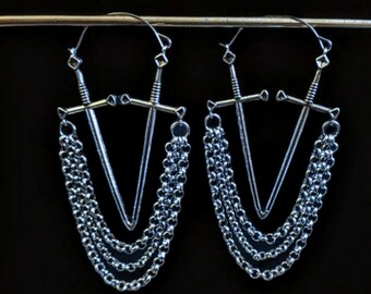 May include: A pair of silver earrings featuring a sword design with multiple chain strands hanging from the bottom.