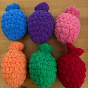 May include: Six colorful, handmade crochet water balloons in a variety of bright colors: blue, purple, pink, orange, green, and red. The soft, textured yarn creates a playful and reusable alternative to traditional water balloons.