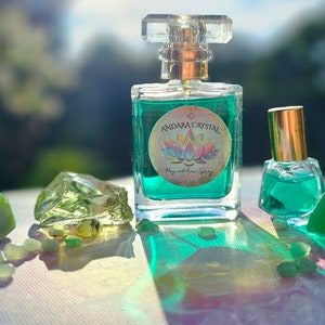 Puede incluir: Dos botellas de l&iacute;quido verde con tapas doradas y etiquetas. La botella m&aacute;s grande tiene una etiqueta que dice "Andara Crystal Magical Aura Spray". Las botellas est&aacute;n rodeadas de piedras verdes.