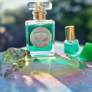 Puede incluir: Dos botellas de l&iacute;quido verde con una etiqueta que dice "Andara Crystal Magical Aura Spray" y un dise&ntilde;o de flor de loto. Las botellas est&aacute;n rodeadas de cristales verdes.