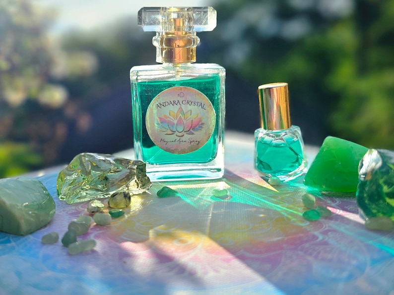 Puede incluir: Dos botellas de l&iacute;quido verde con una etiqueta que dice "Andara Crystal Magical Aura Spray" y un dise&ntilde;o de flor de loto. Las botellas est&aacute;n rodeadas de cristales verdes.