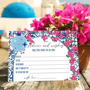 May include: A white card with blue and pink floral and disco ball design. The card reads "Advice and wishes FOR THE SOON-TO-BE MRS" with prompts to fill in advice. A pot of pink flowers sits behind the card.