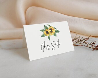 May include: White place card with a watercolour illustration of two sunflowers with green leaves. The text "Ashley Smith" is written in black cursive.
