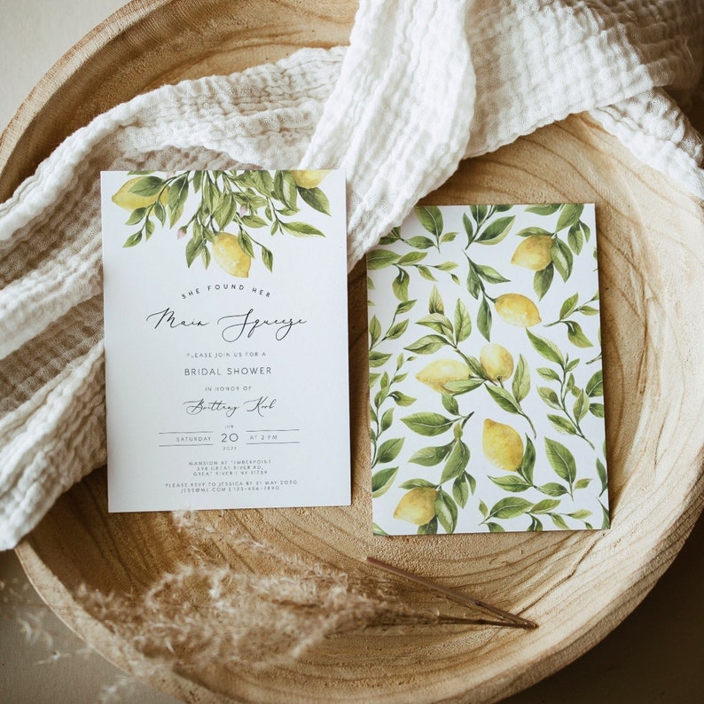 May include: A white card with a lemon motif and the text "She found her Main Squeeze" and "Please join us for a Bridal Shower in honor of Brittany Kul" on a wooden surface.