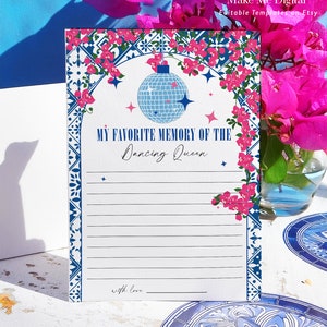 May include: A white card with a blue and pink floral border. The card has a blue disco ball graphic and the text "My Favorite Memory of the Dancing Queen" with a line for writing. The card also has the text "with love" at the bottom.