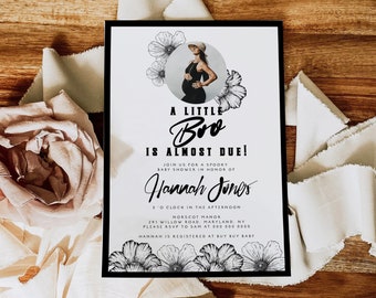 Könnte beinhalten: Eine schwarz-weiße Babyparty-Einladung mit floralen Illustrationen. Der Text lautet "A Little Bro Is Almost Due!" und enthält den Namen "Hannah Jones" sowie Details zur Veranstaltung.