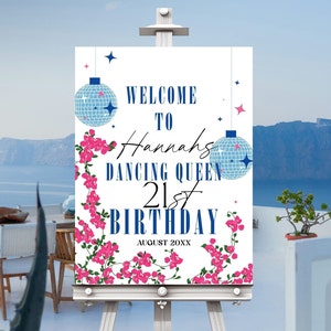 May include: Welcome to Hannah's Dancing Queen 21st Birthday, a white sign with blue and pink floral accents, two disco ball ornaments, and the text "August 20XX".