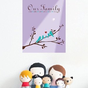 Puede incluir: Una impresión enmarcada con las palabras "Our Family" y los nombres de los miembros de la familia, con una rama de árbol con pájaros turquesa y un corazón rojo. Debajo, una colección de muñecos de tela hechos a mano que representan a una familia.