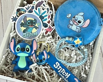 May include: A gift box filled with Stitch-themed merchandise. Includes stickers, a blue coin purse, a bracelet, a keychain, and a figurine. The items are blue and white, with the word "Stitch" on some items.