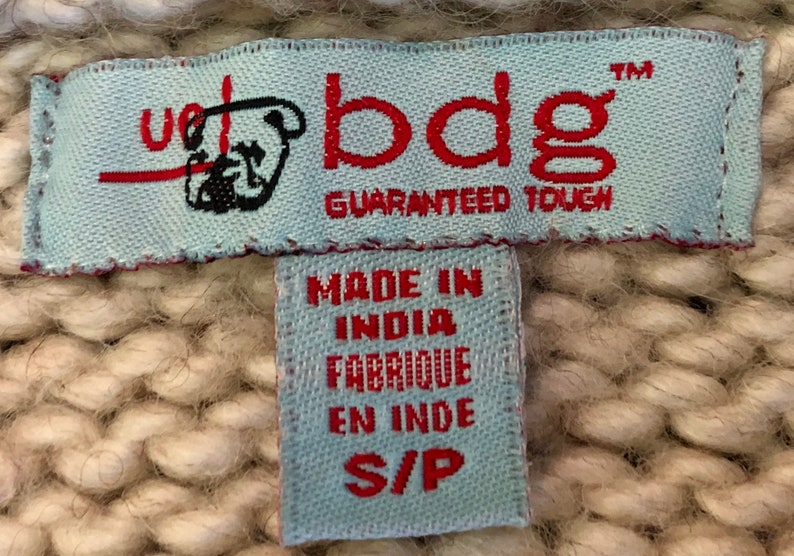 May include: A blue and white woven label with the text "bdg" in red and "Guaranteed Tough" in black. A smaller blue and white label below reads "Made in India Fabrique en Inde S/P".