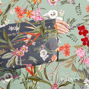 May include: A dark gray fabric with a floral print featuring red, pink, and white flowers, green leaves, and orange and yellow accents. The fabric is draped over a hand and the text "FASHION PRINTS" is visible in the bottom right corner.