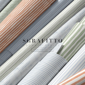 Op de afbeelding: Meerdere rollen stof of behang met diverse organische streeppatronen in kleuren zoals oranje, saliegroen, blauw en grijs. De tekst SGRAFITTO ORGANIC STRIPES TASHISTUDIO.ETSY.COM staat gecentreerd over de diagonale rangschikking.