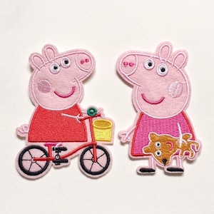 May include: Two pink pig patches. One pig is riding a red bicycle with a yellow basket. The other pig is holding a brown dog. Both pigs are wearing dresses. The patches are embroidered with black and white details.