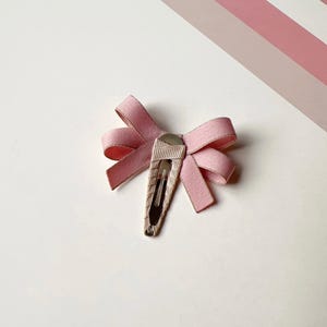 May include: A pink satin bow hair clip with a silver clip.