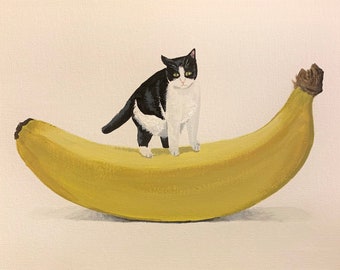May include: A black and white cat stands on top of a large yellow banana. The cat has green eyes and is looking directly at the viewer.