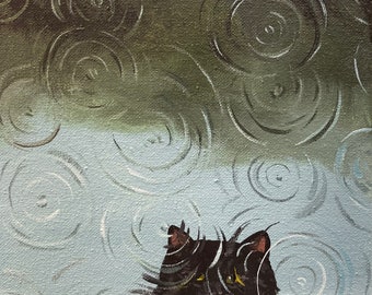 Op de afbeelding: Een zwarte kat met gele ogen kijkt omhoog naar een lichtblauwe en groene achtergrond met een patroon van concentrische cirkels. De cirkels zijn in lichtgrijs geverfd.