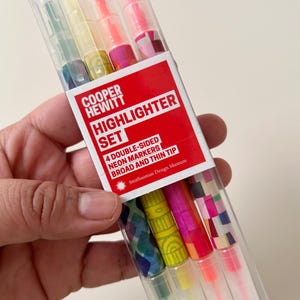 May include: A clear plastic package containing a set of four double-sided neon highlighters. The highlighters have broad and thin tips and are labeled "COOPER HEWITT HIGHLIGHTER SET" with the Smithsonian Design Museum logo.