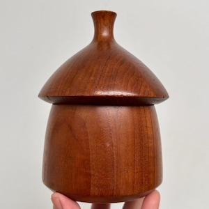 May include: A white ceramic mug with a black handle and the text "But First, Coffee" in a black, bold font. The mug is sitting on a white surface.