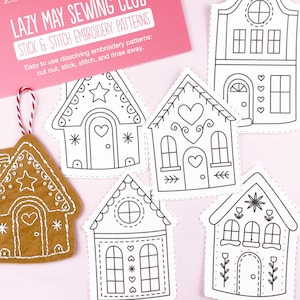 May include: A selection of stick and stitch embroidery patterns with house motifs. The patterns are in black and white, showcasing different house styles with hearts and stars. A gingerbread house ornament is also included. The text "LAZY MAY SEWING CLUB" is visible.