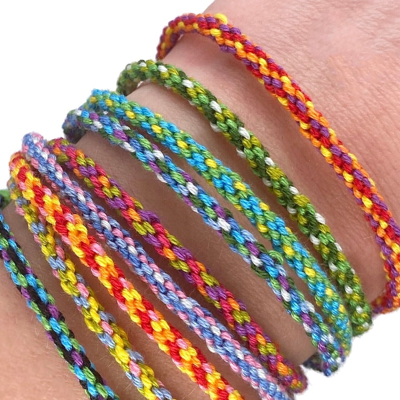 A closer look at the finished bracelets stacked on a wrist. The rainbow colours really pop and each one is made using the simple wooden loom included in the kit — a joyful, wearable result from a relaxing craft.