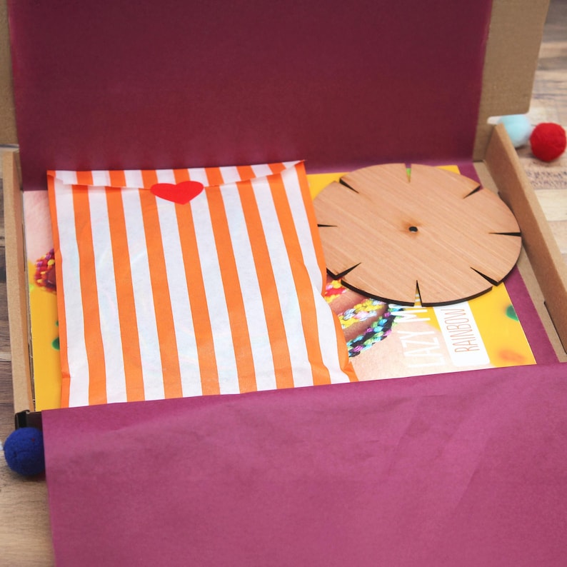 The bracelet kit being opened to reveal its contents — colourful threads, wooden loom and instructions. A thoughtful DIY gift or fun project to enjoy together at home.