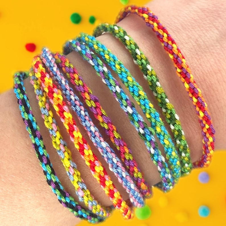 A colourful stack of handmade friendship bracelets wraps around a wrist, all created using the bright rainbow threads and wooden loom included in our easy DIY bracelet-making kit for kids, teens and adults.