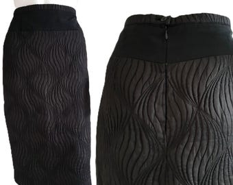 Pode incluir: Saia lápis preta com um padrão acolchoado texturizado. A saia apresenta uma cintura larga e preta lisa e um fecho de correr nas costas. O design acolchoado cria um padrão ondulado no tecido. Uma peça clássica e versátil.