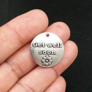 Peut inclure: Breloque en argent avec le texte "Get well soon" et un petit motif de fleur.