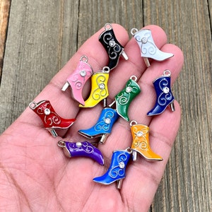 Può includere: Assortimento di dieci ciondoli a forma di stivale in smalto colorato con dettagli in strass. Ogni ciondolo presenta un colore diverso e un design intricato.