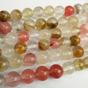 May include: A strand of round, translucent beads in shades of pink, brown, and white. The beads have a natural, slightly cloudy appearance.