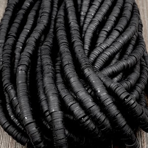 May include: A close-up of a pile of black rubber beads. The beads are round and have a smooth, glossy finish.