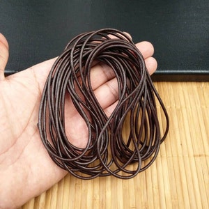 Puede incluir: Primer plano de un manojo de cordón de cuero marrón. El cordón tiene aproximadamente 2 mm de grosor y es ideal para hacer joyas, llaveros y otros accesorios.