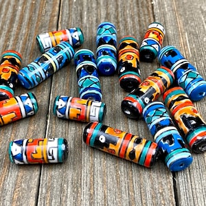 May include: A collection of colorful ceramic beads with geometric patterns in shades of blue, orange, yellow, and black. The beads are cylindrical in shape and have a glossy finish.