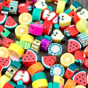 May include: Assortment of colorful fruit-shaped polymer clay beads. The beads are in various shapes, including watermelon, lemon, apple, pear, and kiwi. The beads are perfect for jewelry making, crafting, and other DIY projects.