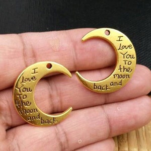 Colgante con dos dijes de media luna en color dorado con la frase "Te amo hasta la luna y más allá", frases inspiradoras, mensajes, motivación y joyas