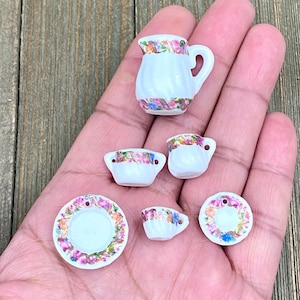 Puede incluir: Un juego de té de porcelana en miniatura con un diseño floral. El juego incluye una jarra, dos tazas, dos platillos y un azucarero.