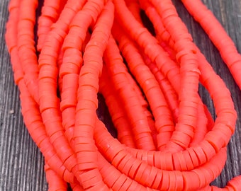 May include: A close-up of a pile of bright orange round polymer clay beads. The beads are stacked on top of each other, creating a textured and colorful display.